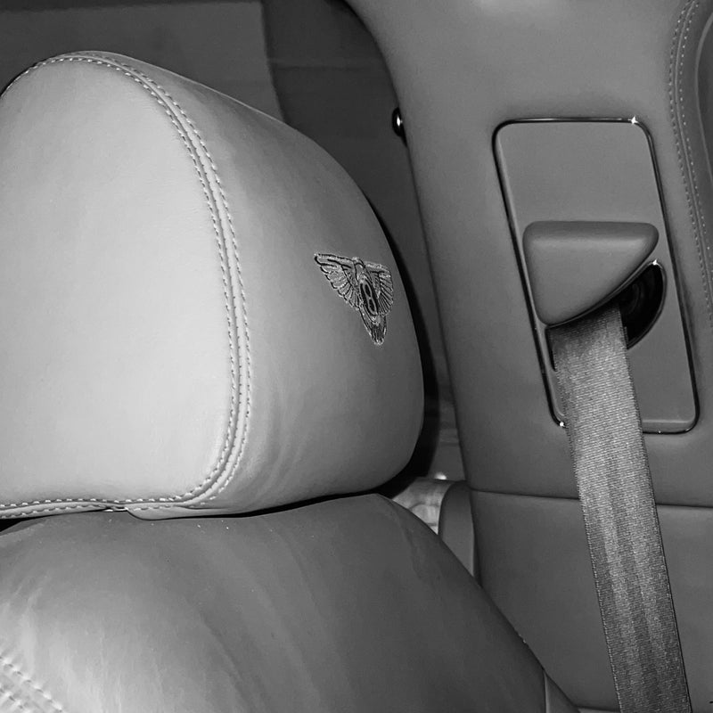 Car interior with gray seats and a visible Bentley logo.